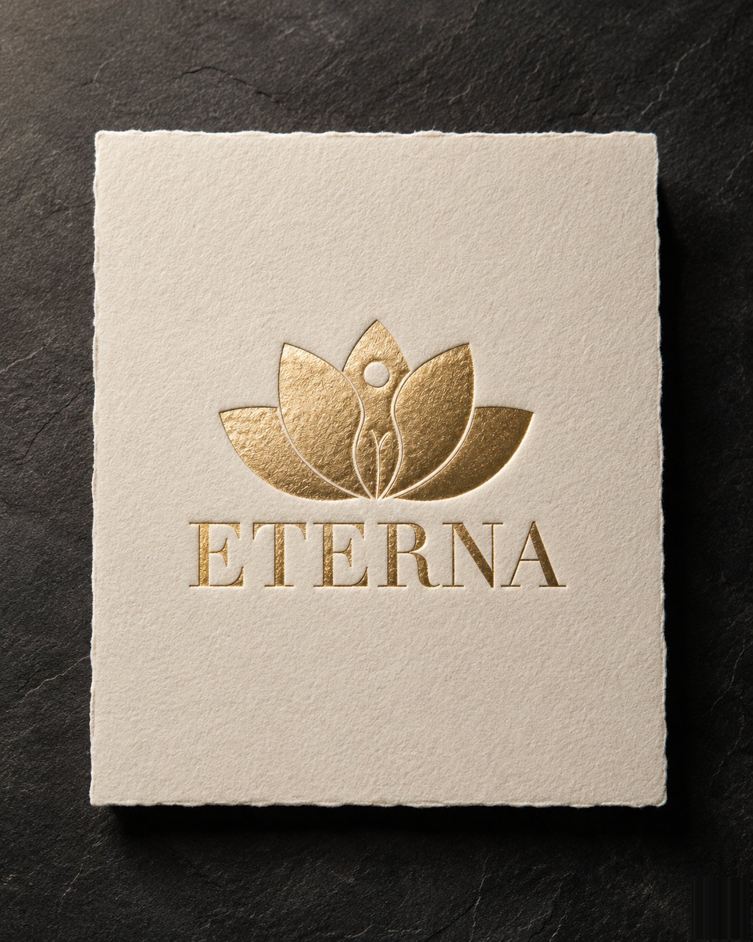ETERNA gold-foil monogram and wordmark on a heavy cream card photographed on dark slate