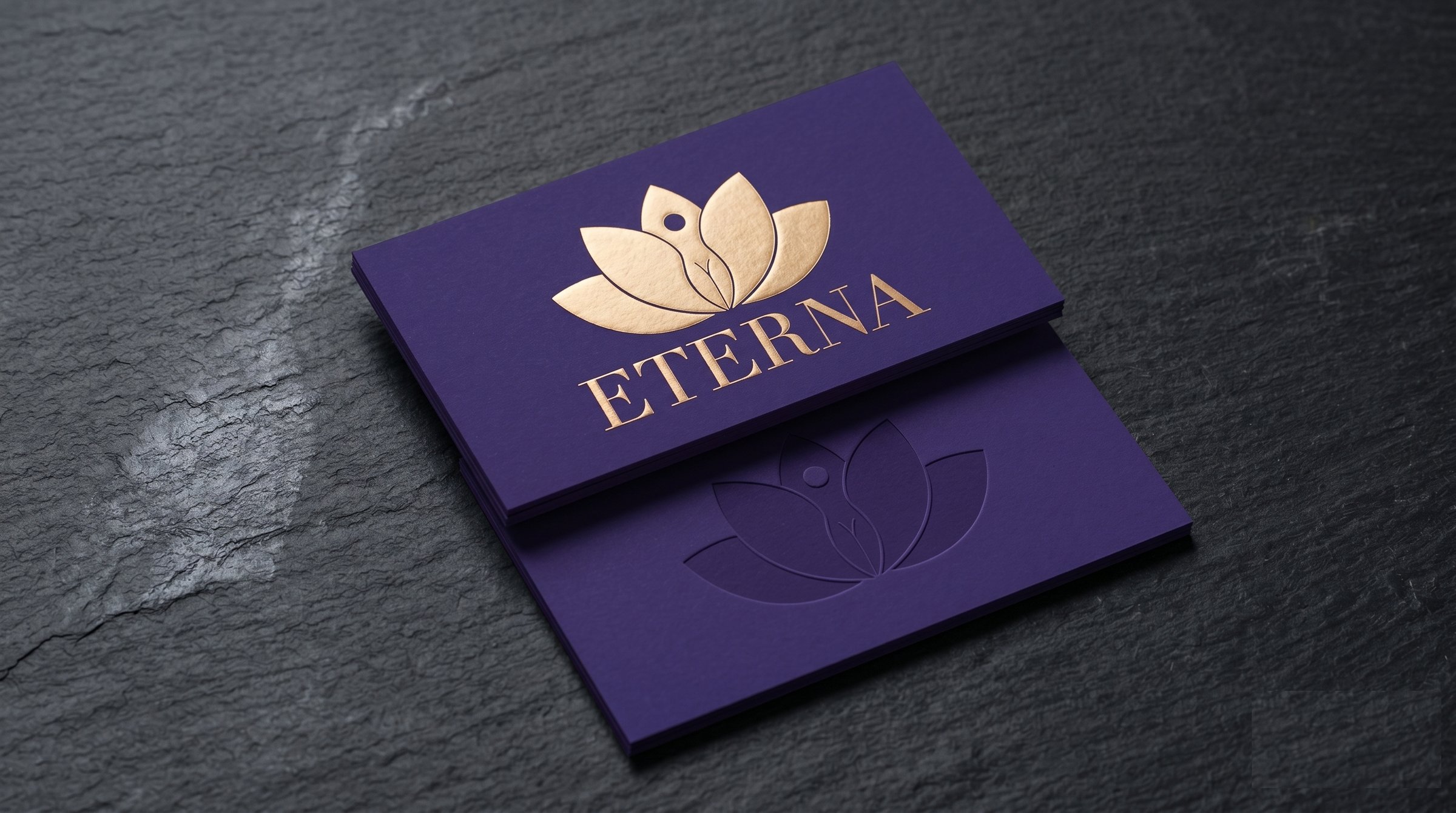 ETERNA royal-purple business cards stacked at 30 degrees with gold-foil monogram