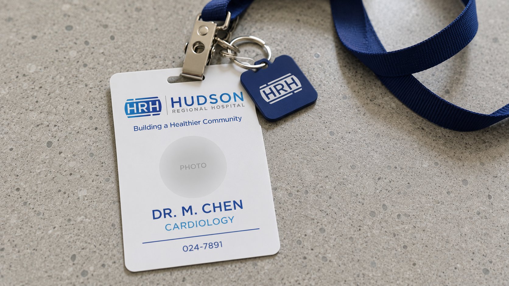 Brand visualization of a Hudson Regional Hospital staff ID badge and key fob on a navy lanyard